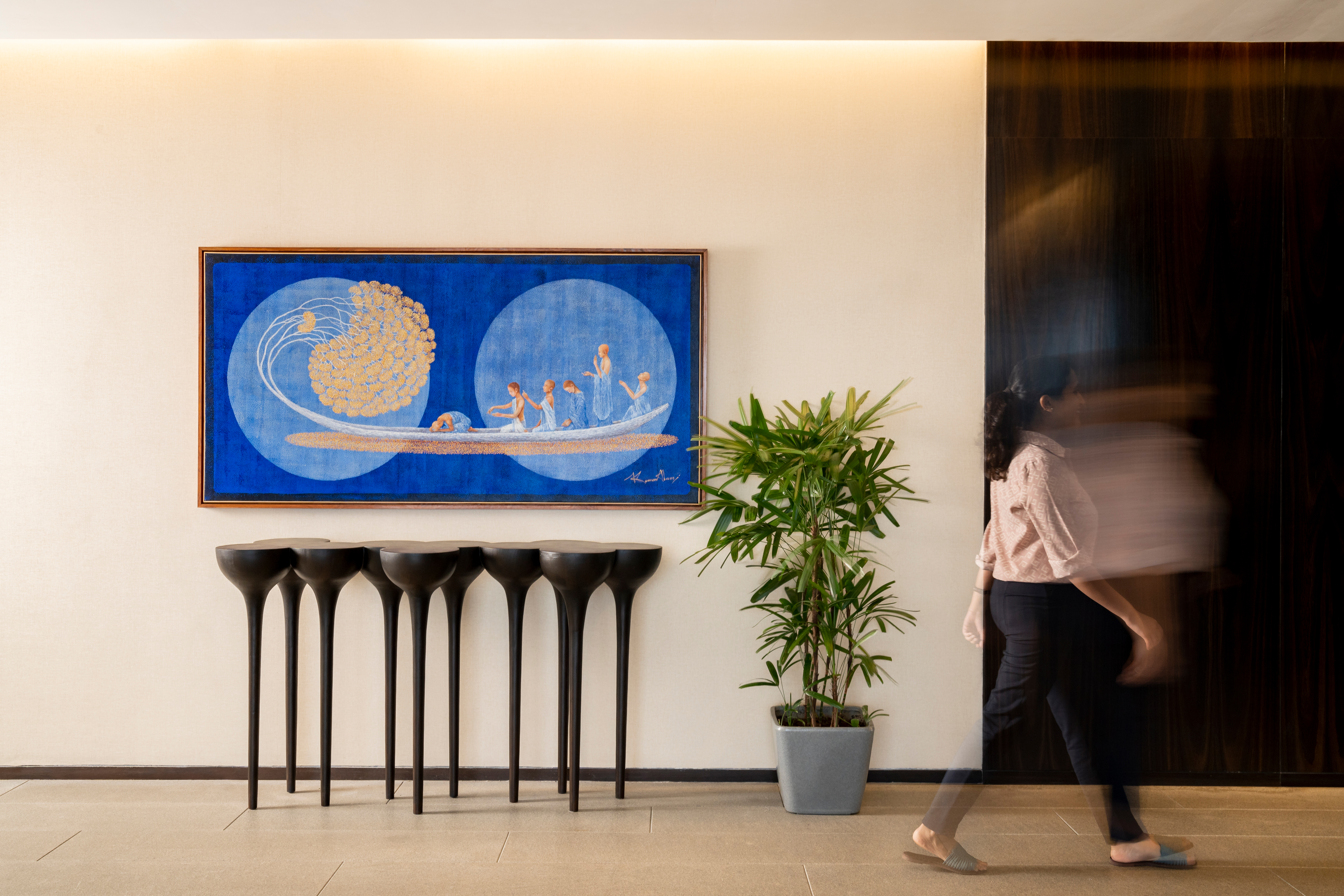 A large blue artwork in a corporate lobby with a passing figure in motion — Artemist Consultancy, commercial